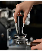 Black espresso tamper tool pressing into a portafilter basket