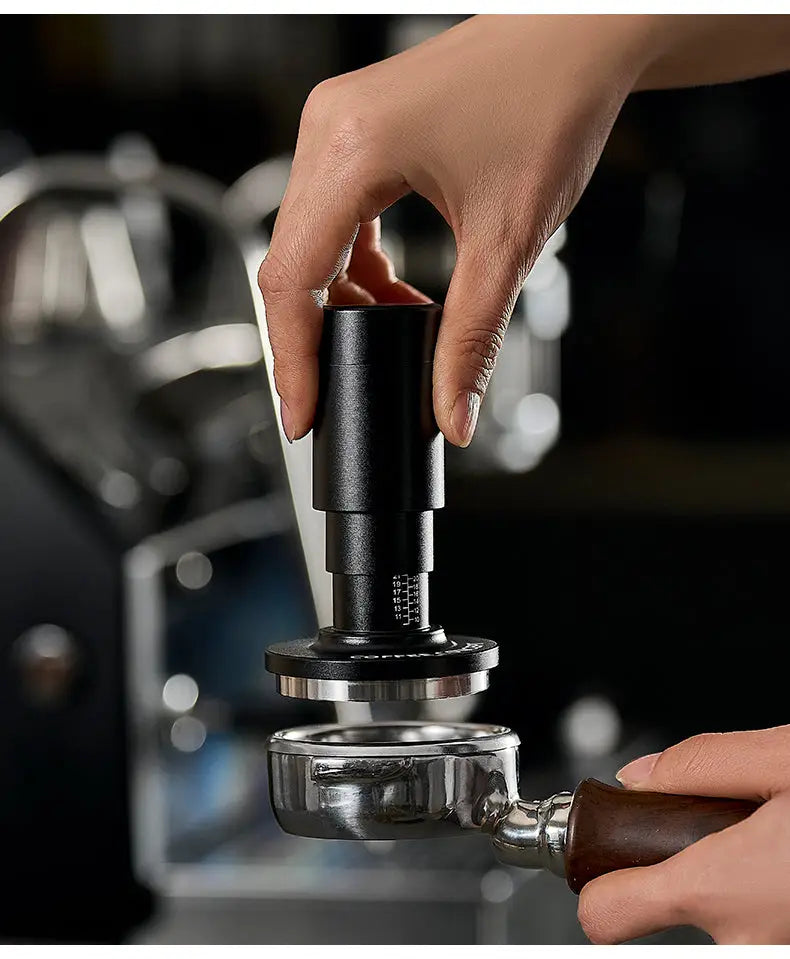 Black espresso tamper tool pressing into a portafilter basket