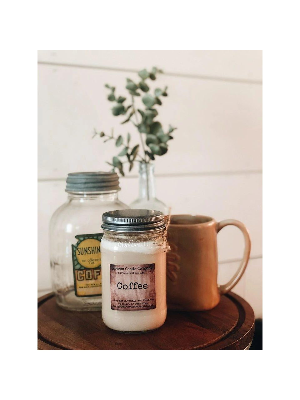 Coffee candle jar with “Coffee” label on a round tray with mug and plants