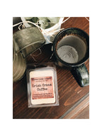 Soy wax melt clamshell labeled 'Irish Cream Coffee' with a wax warmer nearby