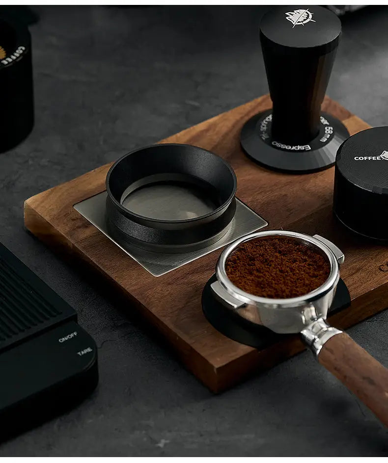 Black magnetic anti-static espresso dosing ring on a wooden stand with tools