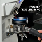 Black magnetic espresso dosing ring attached to a stainless coffee funnel, with handle grip visible.