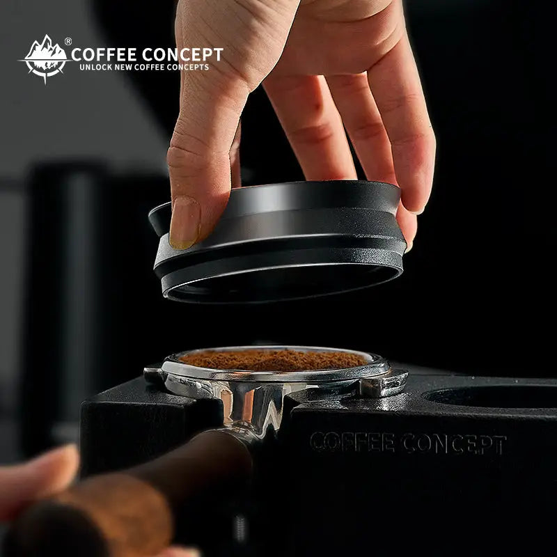 Black magnetic espresso dosing ring held above a portafilter basket with ground coffee.
