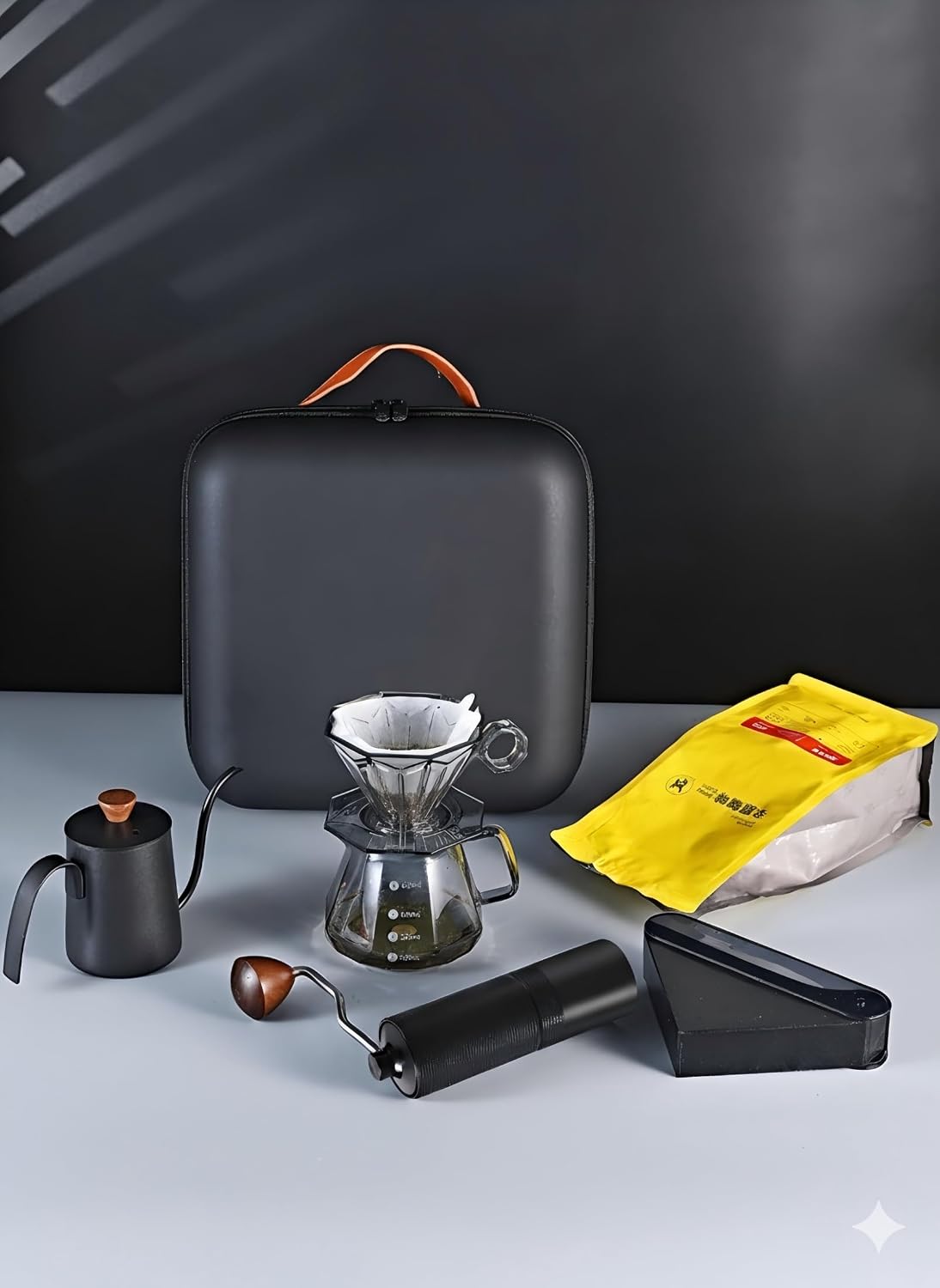Travel pour-over coffee kit with black dripper, carafe, kettle, grinder, and coffee bag