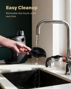 Black espresso machine with removable drip tray being rinsed at sink, stainless faucet