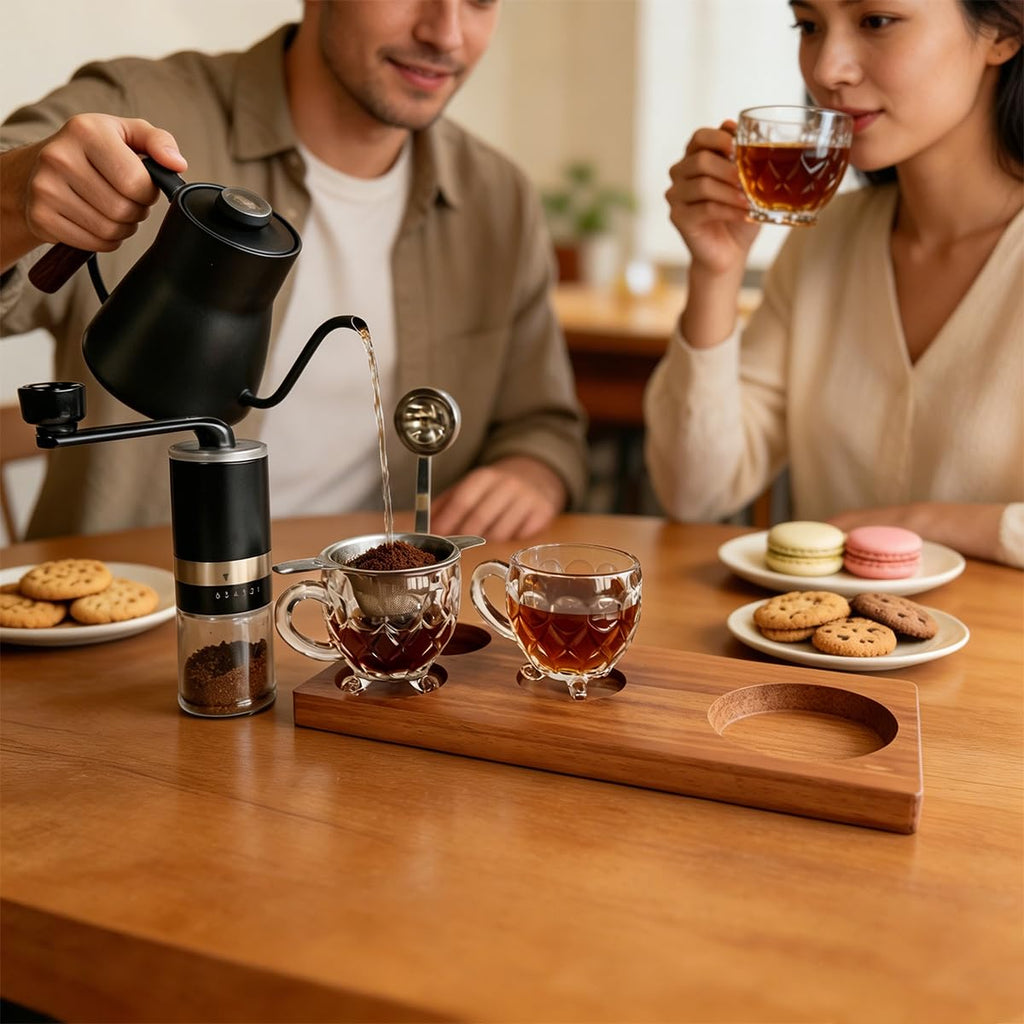 Pour-over coffee setup on wooden tray with gooseneck kettle, dripper, and two glass cups
