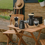 Outdoor coffee table set with black kettle, glass carafe, and pour-over dripper