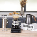 Stainless and black pour-over coffee kit with dripper, kettle, grinder, and glass carafe