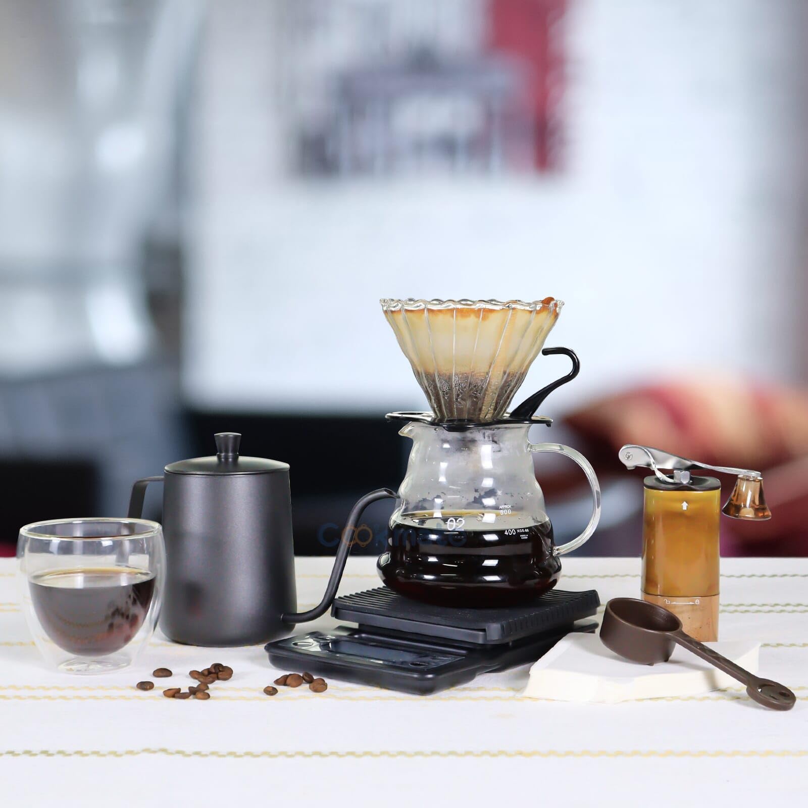 Pour-over coffee equipment set with glass dripper, dark kettle, grinder, and cups