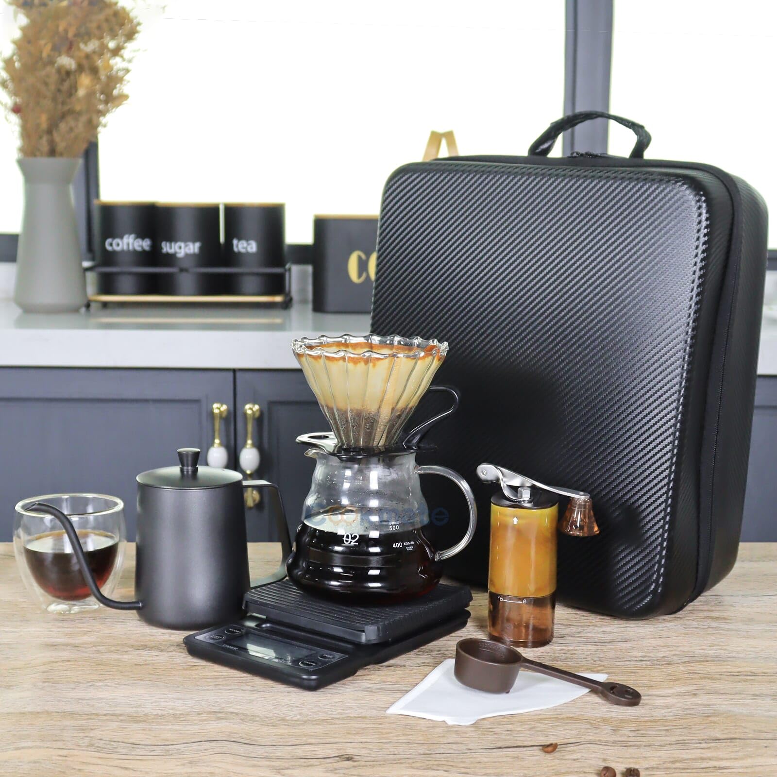 Countertop pour-over coffee brewer with glass carafe, kettle, and black zippered travel case