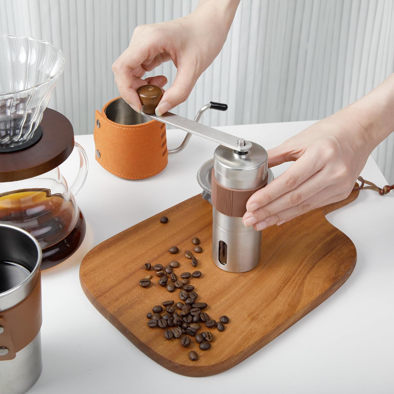 Pour-over coffee brewing kit with gooseneck kettle pouring into glass dripper beside grinder
