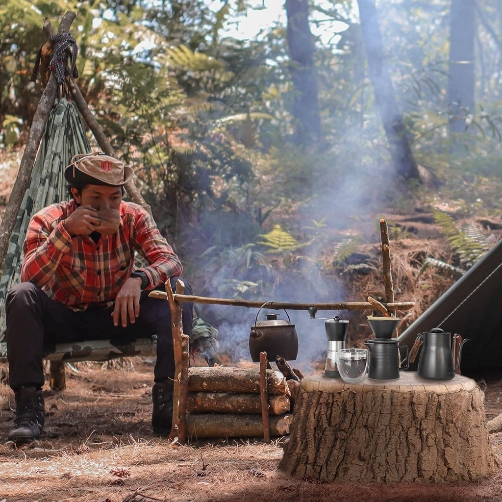 Camping pour-over coffee station with kettle, dripper, and brewing tools on stove