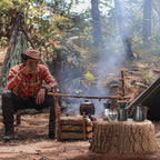 Camping pour-over coffee station with kettle, dripper, and brewing tools on stove