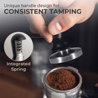 Espresso tamper with black handle held over portafilter, showing integrated spring