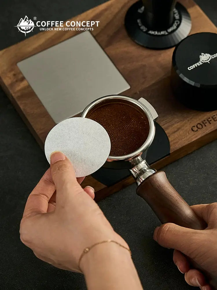 White circular coffee filter paper disc held above a stainless portafilter basket