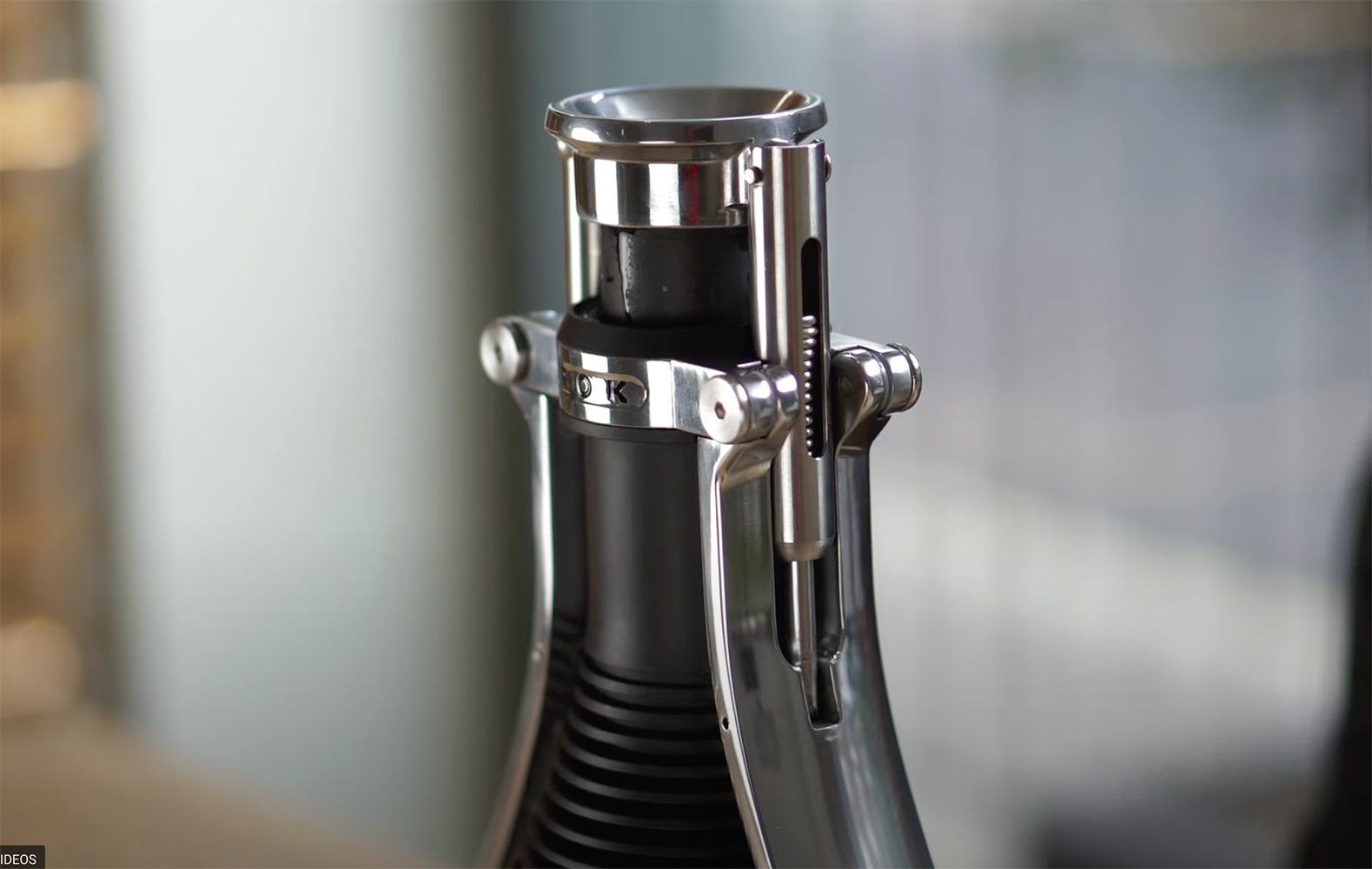 Stainless and black manual espresso maker close-up of top chamber and press lever