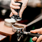 Spring-loaded espresso tamper pressing down on espresso grounds in portafilter